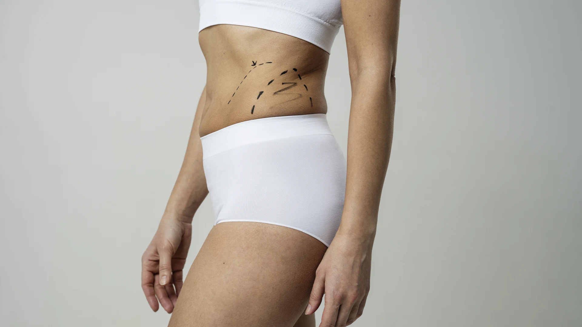 A happy mother looking at herself in the mirror, regaining body confidence after pregnancy or weight loss.